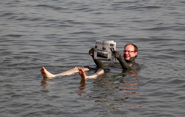 A European tourist reads a newspaper as he bathes in the Dead Sea on a sunny day with a temperature of 25 Celsius degrees (77 F) in Kalya on February 12, 2010.  AFP PHOTO/GALI TIBBON (Photo credit should read GALI TIBBON/AFP/Getty Images)